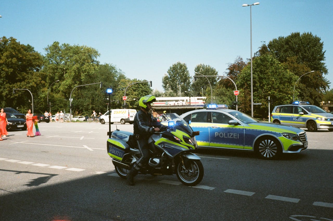 German police presence with cars and motorcycle during daytime traffic control.